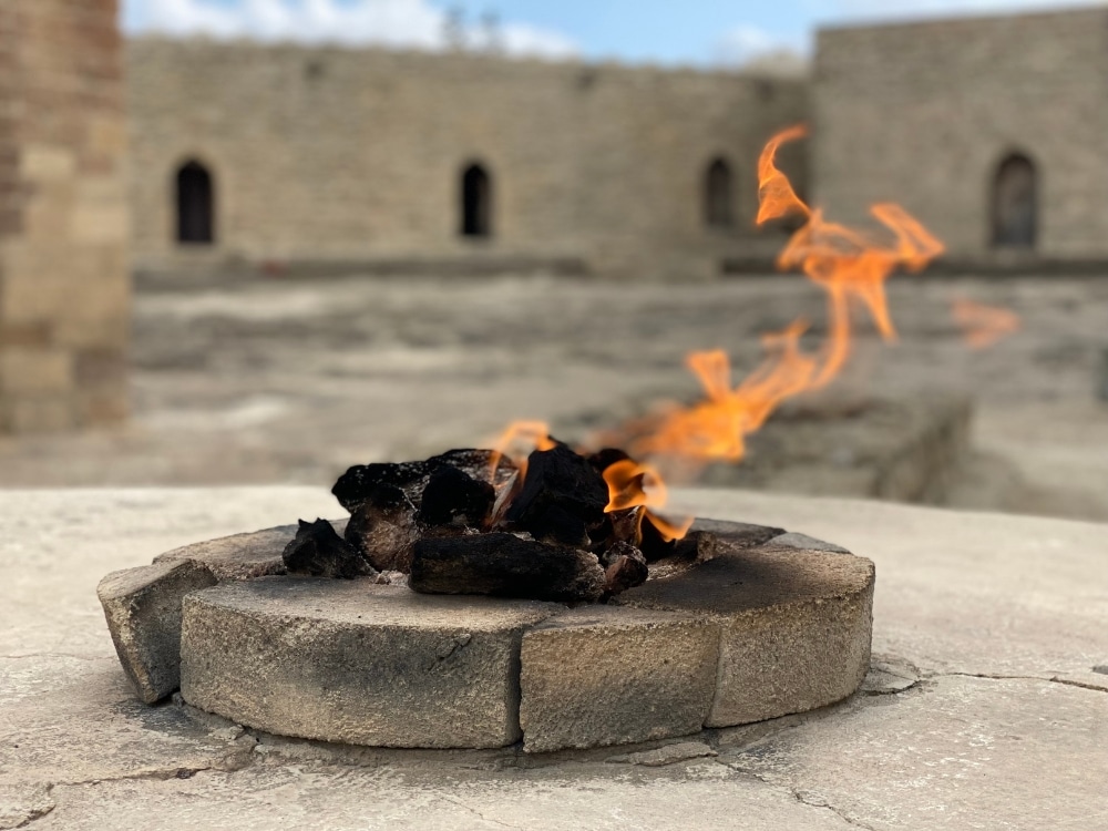 small fire pit surrouned by stone and ancient buildings