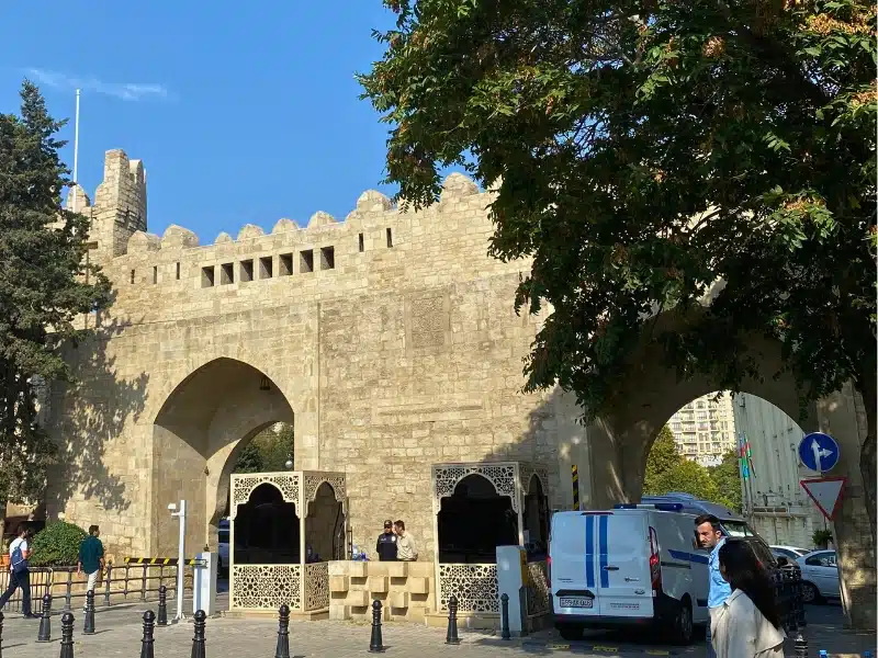 large stone gates in a stone wall with a crenellated top. 