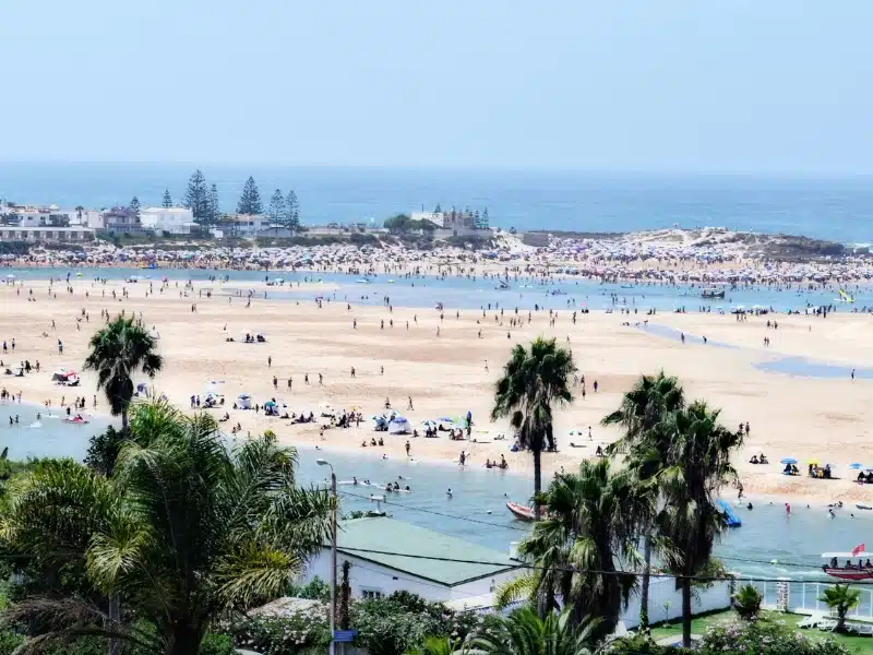 large and busy sandy beach with a lagoon on one side and the sea on the other