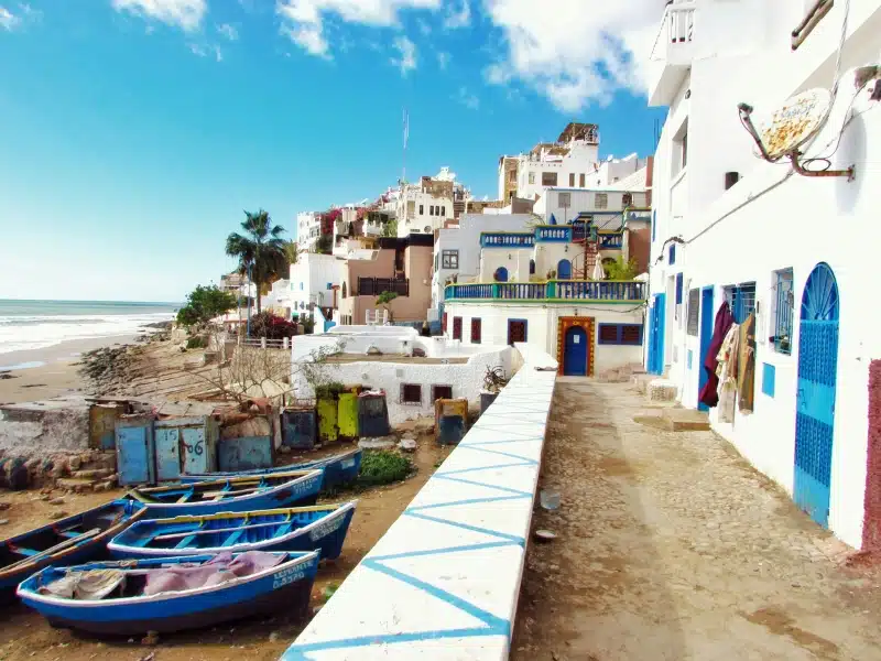 colorful beachside row of houses with blue boats at the shore