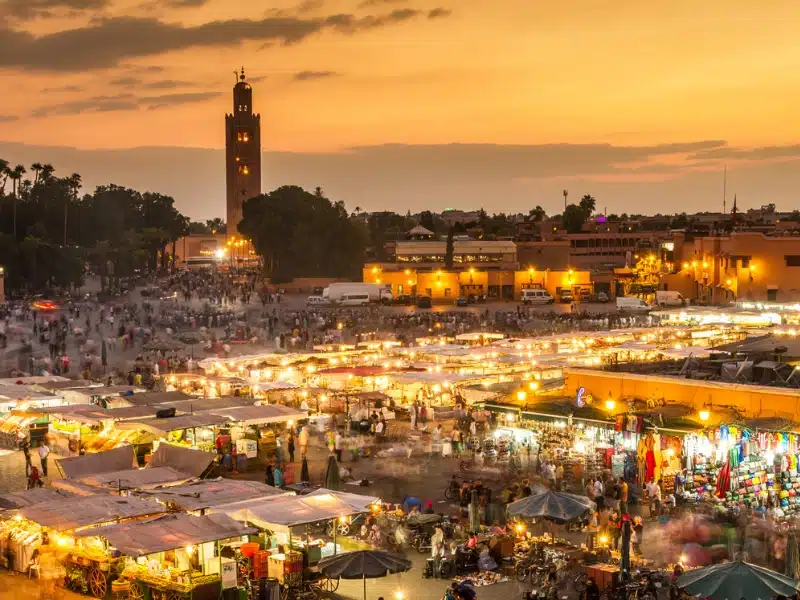 dusk over a busy night market with a minaret in the distance