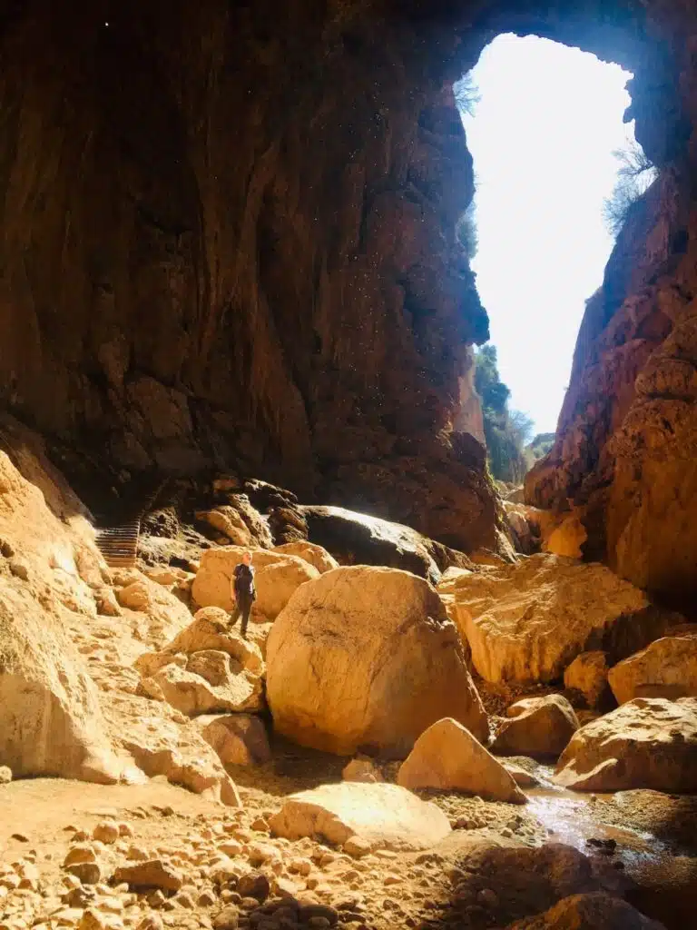 large cave filled with big limestone boulders and a man standing one one of them