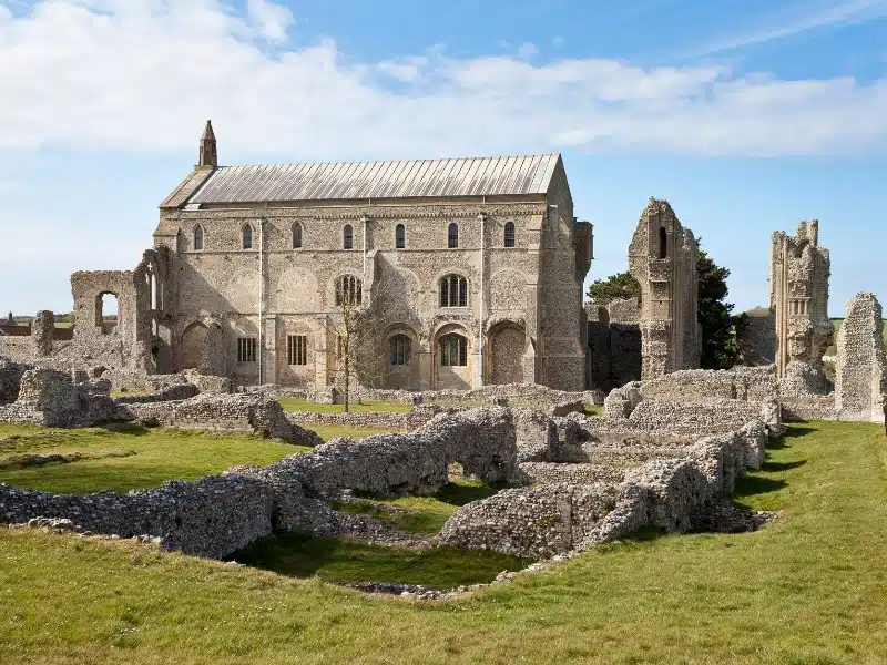 ruins of a priory with a mainly intact church all surrouned by grass