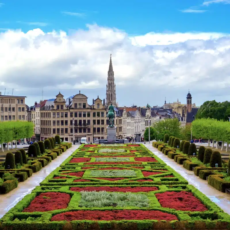 formal flower beds with a statue of a man on a horse and a tall spire in the background