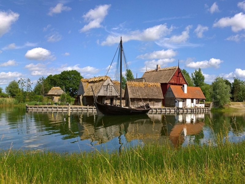 baot on a river backed by small thatched houses in a traditional Danish style