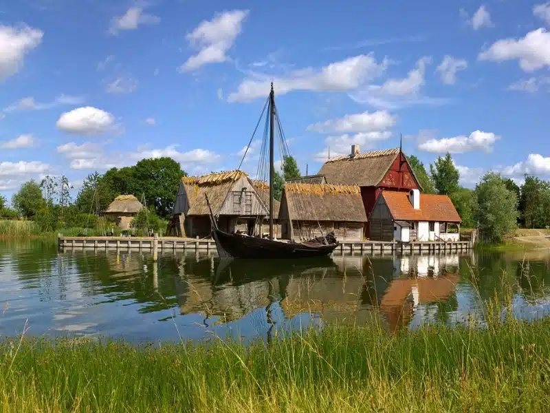 baot on a river backed by small thatched houses in a traditional Danish style