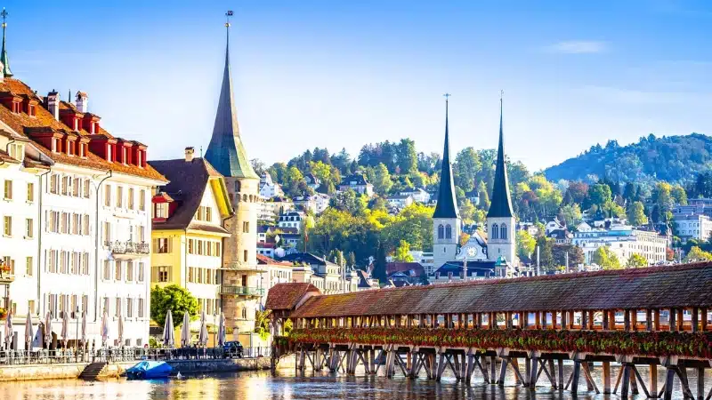 large covered bridge over water, with buildings and churches in the background