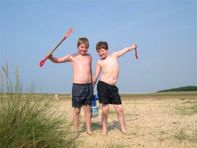 two boys playing on a beach with buckets and spades