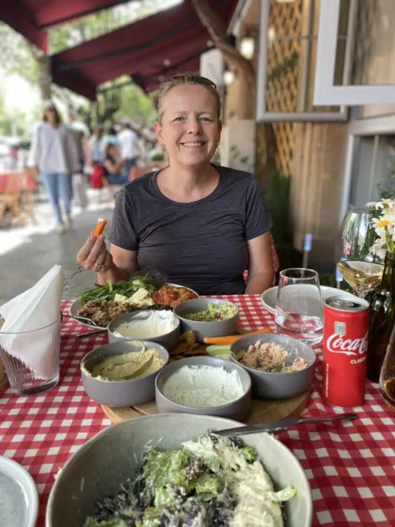 woman at a table with a red and white tablecloth and dishes of different foods