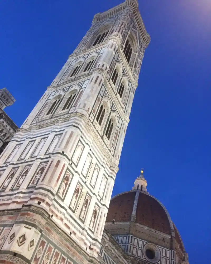 black white a pink tower stretching into a twilight blue sky with a dome behind