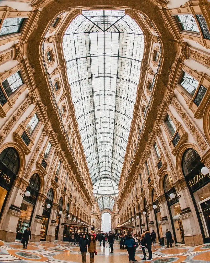 large glass and steel arched structure with shops lined a tiledwalkway