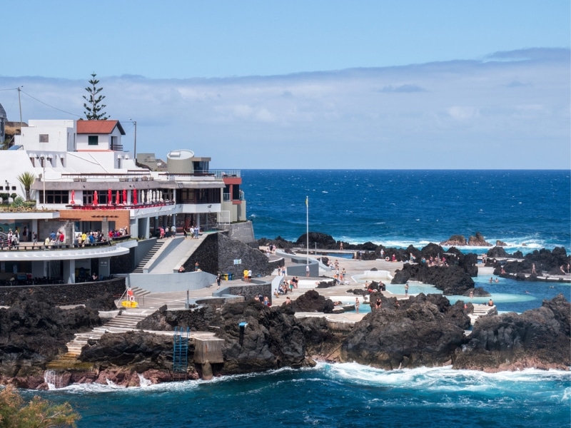 blue sea with people swimming in  naturally fomed pools of volcanic rock