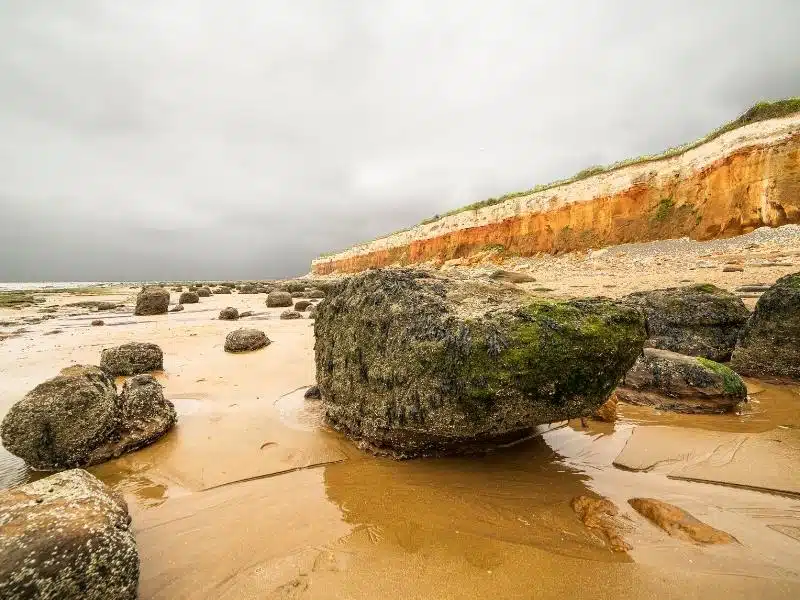 red and white striped cliffs behind a rocky beach