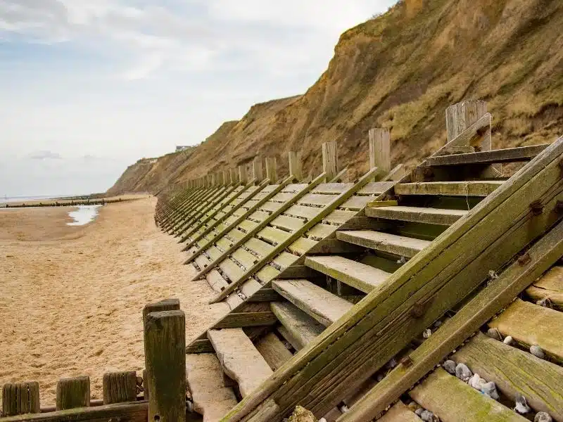 wooden stairs and sea defences against a beachside cliff