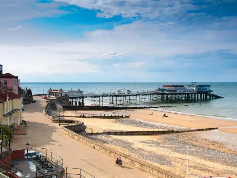 long pier jutting out to sea with a beach and town behind