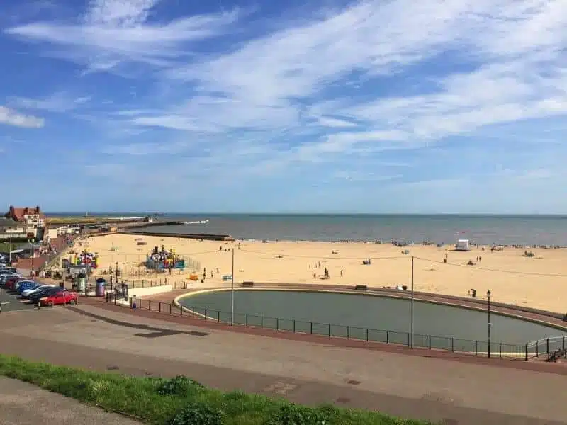 resort beach with small pond by the prom and cars parked along the road