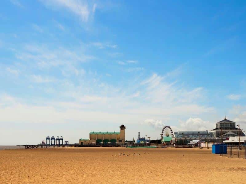 wide view of a beach with a fun fair and Ferris wheel in the distance