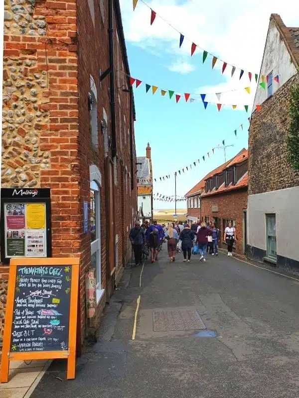 narrow street with brick buildings and people walking to a harbour