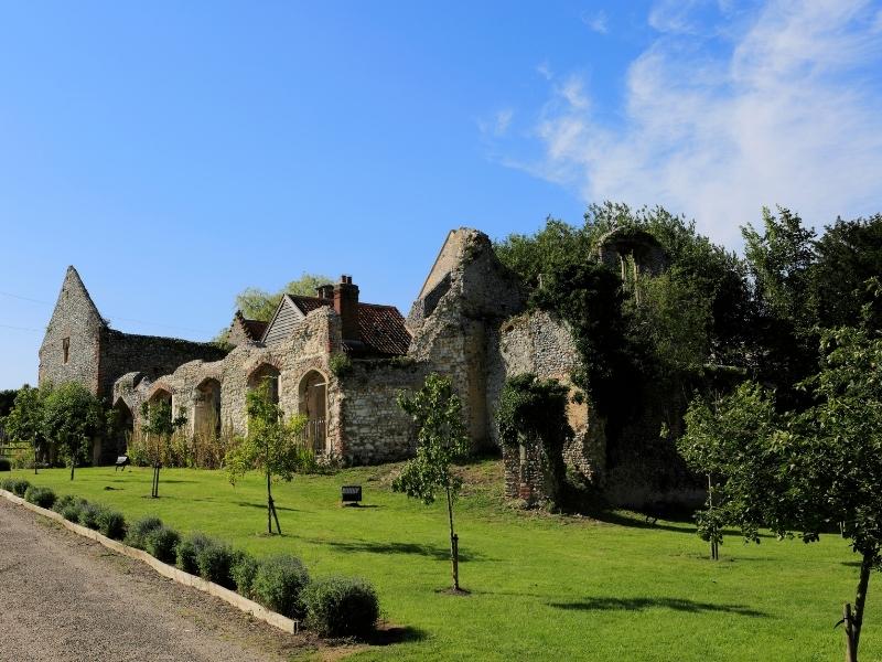 priory ruins surrouned by grass and newly planted trees