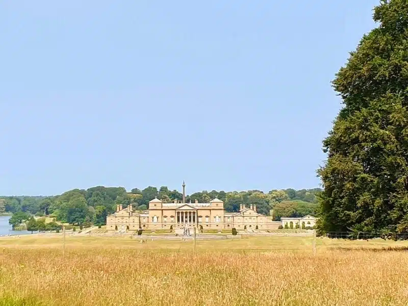 large stately home seen over a field of grasses