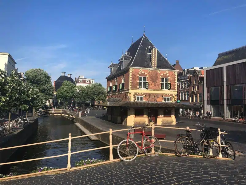 traditional Dutch building by a canal with a bridge and bikes in the foreground