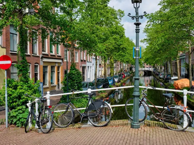 bicycle on bridge and canal with cars parked along in the street 