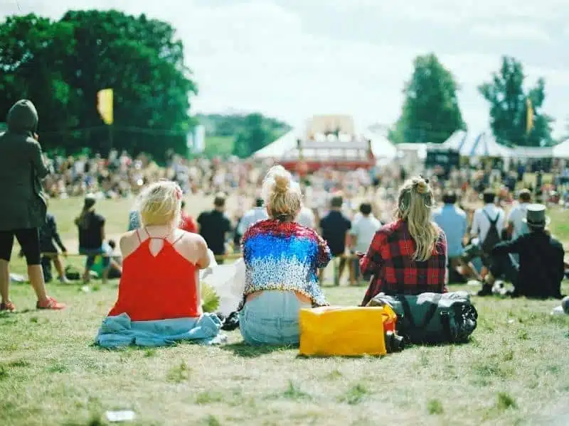 three blonde women in a row facing a festival stage