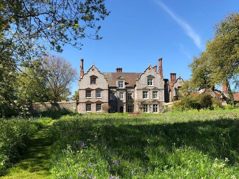 Small Tudor hall set in informal gardens with wildflowers