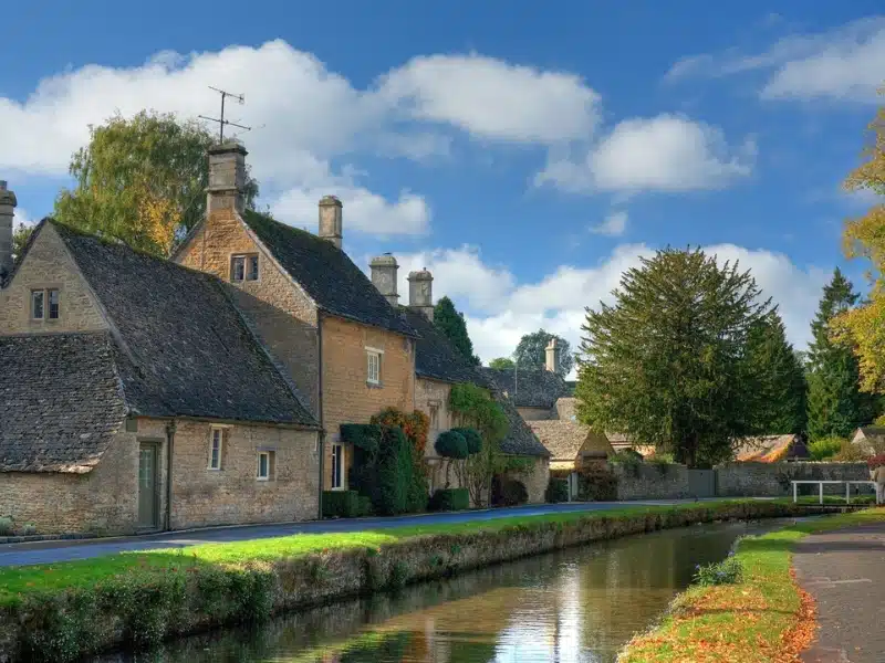 small stream running through a village with stone buildings and trees