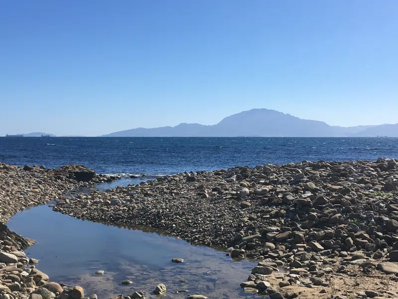 Pebbles, blue sea and mountains in the distance