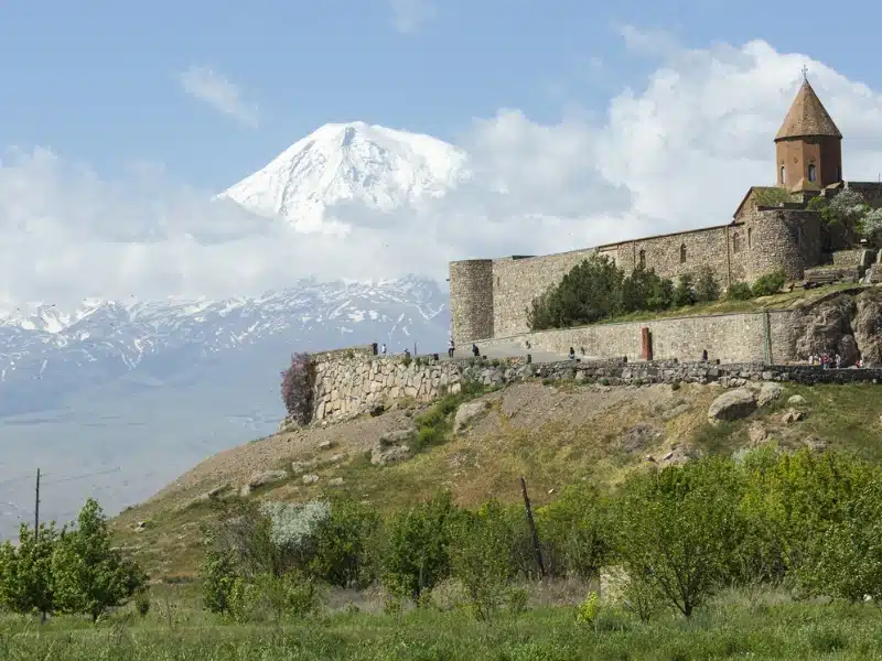 stone built monastery in front of a large snow capped mountains