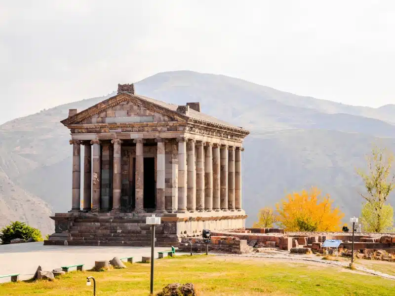 Greek temple with many colums backed by mountains