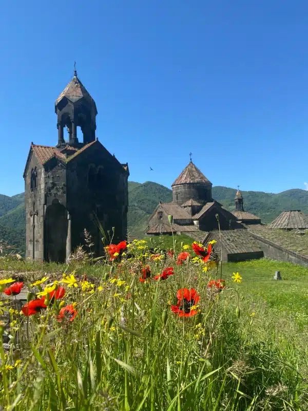 ancient Armenian monastery with wooden mountains as a backdrop and wildflowers in the foreground