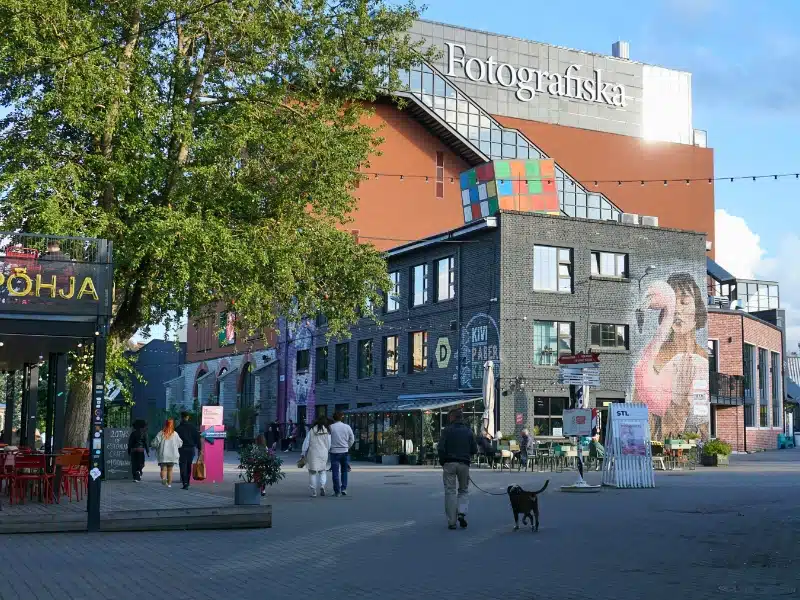 People walking in Telliskiviwith a mix of modern and older buildings around a small square