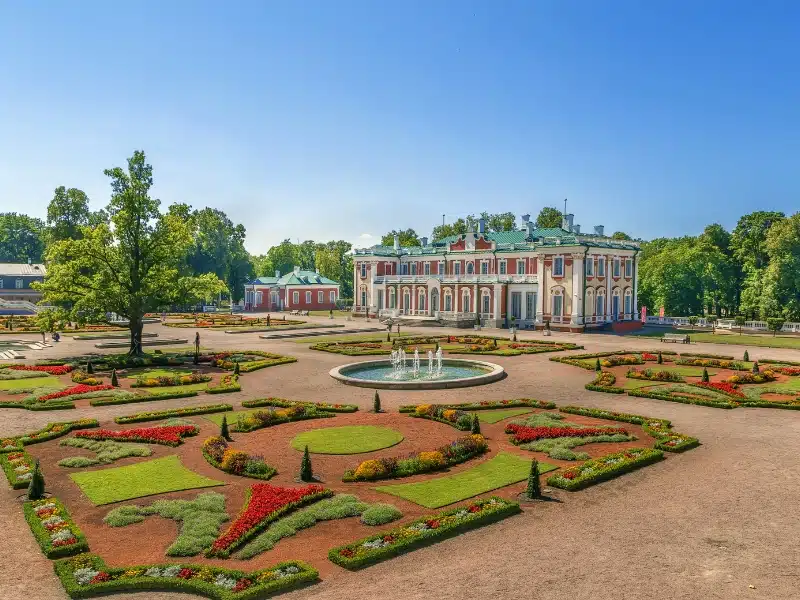 red and green palace surrouned by formal flower beds and fountains