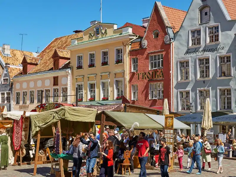 row of colorful historic houses in a square with a busy market in front