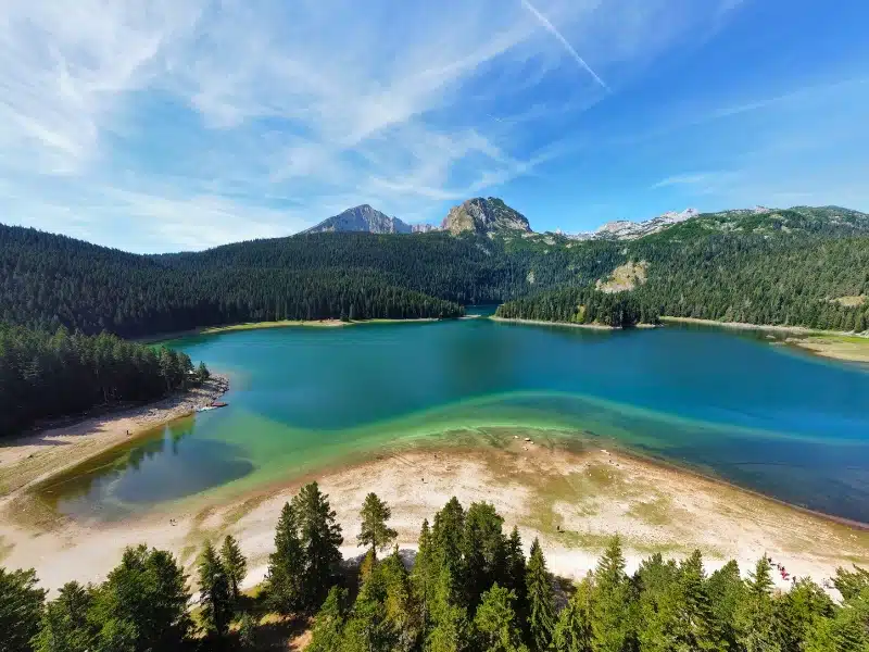 aerial view of a large lake surrouned by forests and mountains