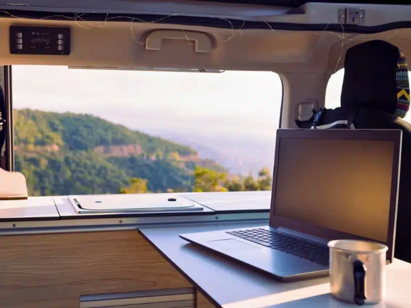 table in a van with a laptop and coffee cup