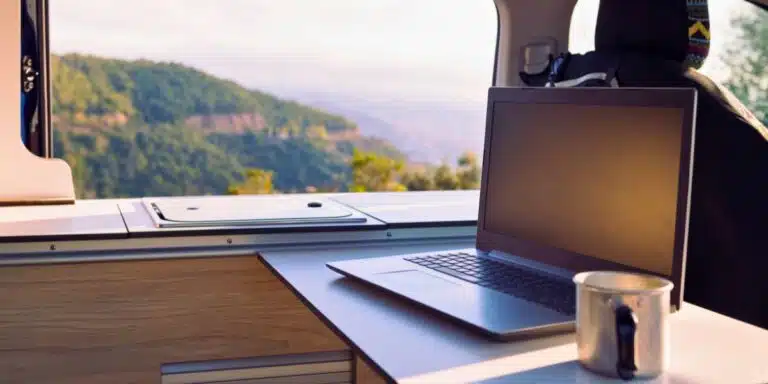 table in a van with a laptop and coffee cup