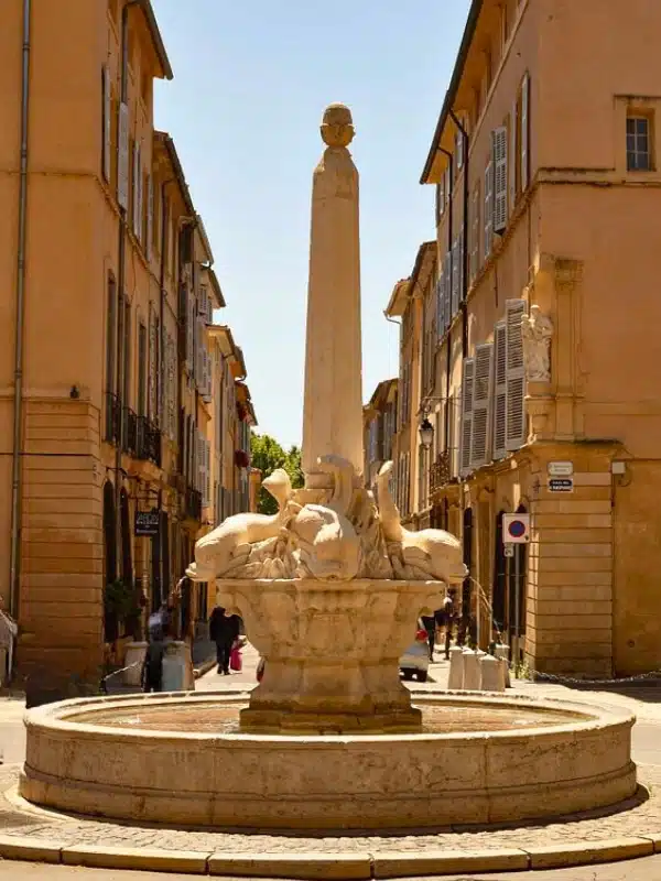 sandstone fountain with carved dolphins and a central obelisk