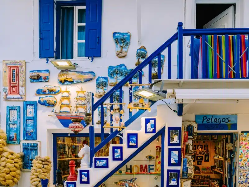 Traditional narrow colorful street with blue doors and white walls, shopping street, Mykonos town Greece