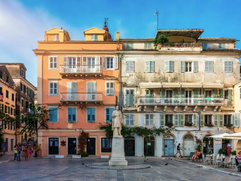 Pastel painted historic buildings with shutters and balconies on a square in Corfu Town