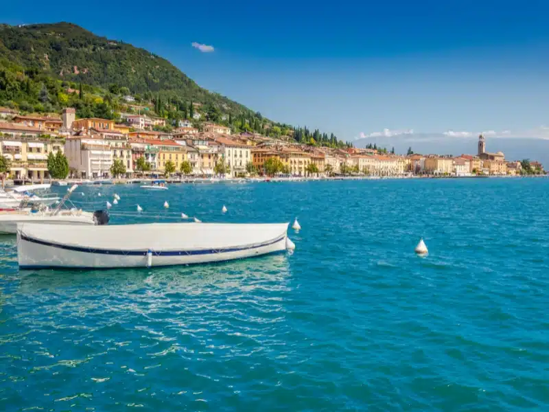 Idyllic lake Garda coastline and mediterranean village of Toscolano Maderno with sailboats and mountains, Northern Italy