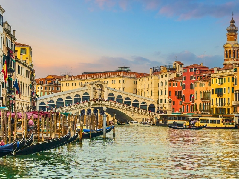 Panoramic view of famous Grand Canal and Rialto Bridge at sunset in Venice
