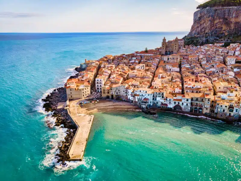 Drone view from above at the old town of Cefalu on a sunny day, medieval village of Sicily island, Province of Palermo, Italy. Europe