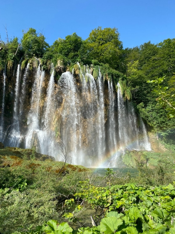 large waterfall into a turquoise pond with a rainbow