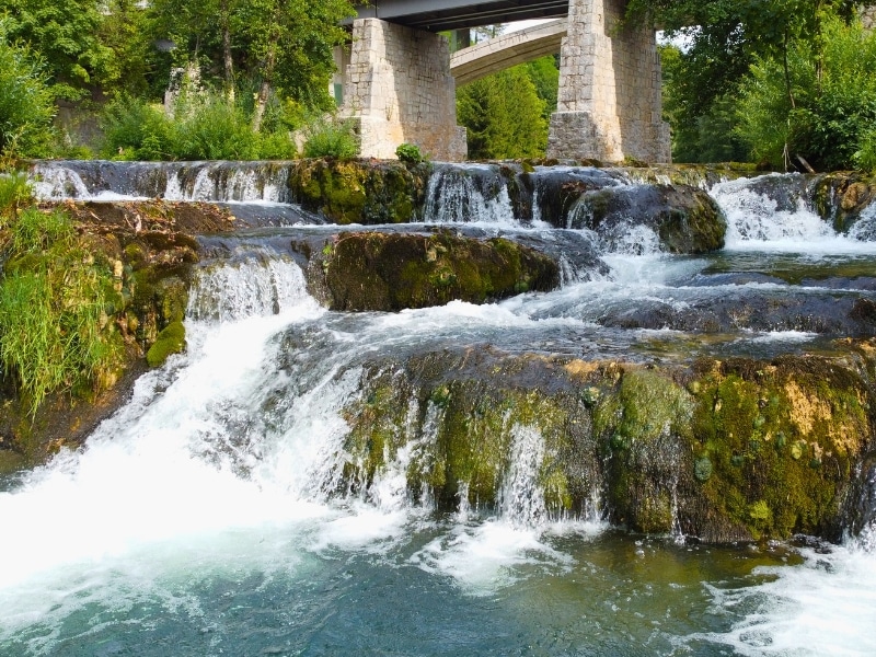 multiple small waterfalls under a stone bridge