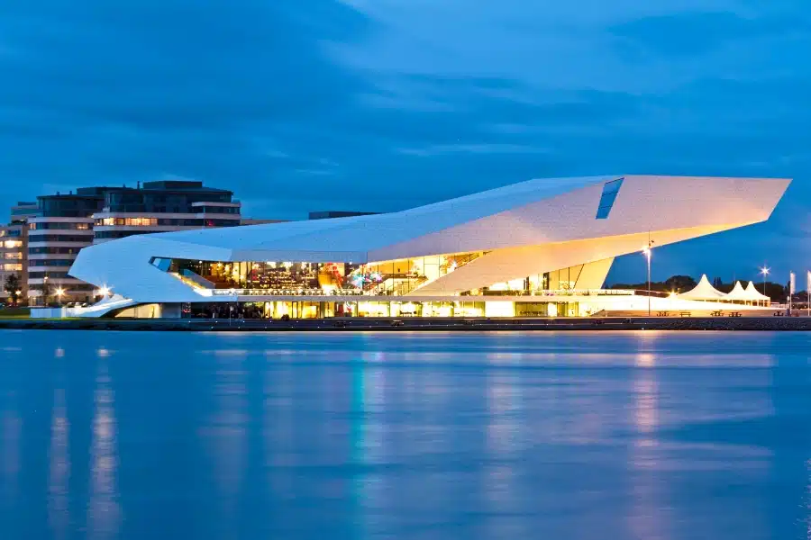 contemporary white musuem building at dusk with the lights shining across the water of a wide river