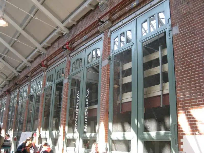 People sitting in an indoor market with brick buildings with green windows