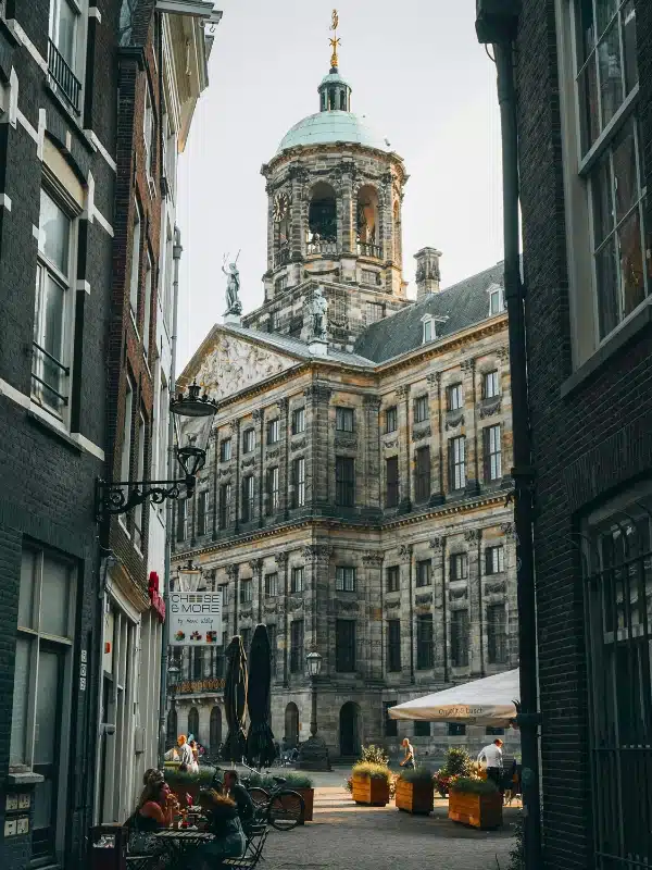 Large domed historic building on a cobbled square seen from a nearby alleyway